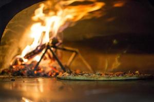 pizza perto do fogão de pedra com fogo. fundo de um restaurante pizzaria tradicional com lareira. foto