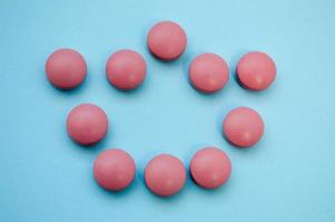 coroa convexa volumosa rosa disposta em comprimidos em um fundo azul brilhante. contágio do coronavírus. preparações tópicas para tratar uma pessoa de uma infecção viral foto