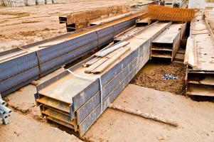 muitos materiais de construção com peças sobressalentes de metal, varas, vigas, tubos em um armazém de canteiro de obras ao ar livre foto