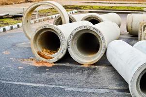 grandes tubos de encanamento de esgoto de concreto pedra cimento de grande diâmetro para a construção industrial de abastecimento de água ou esgoto em um canteiro de obras durante o reparo foto