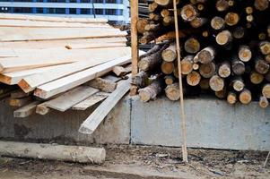 muitos troncos e tábuas aplainadas naturais de madeira longa em uma serraria. o fundo. textura. colheita de madeira de conceito para a indústria madeireira foto