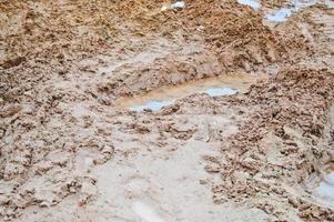 textura de uma estrada de terra suja e ruim com poças e lama de secagem de argila com rachaduras e sulcos. fora da estrada. o fundo foto