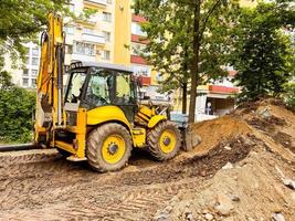 escavadeira amarela brilhante cava um buraco na areia. máquinas de construção. veículo confiável para a construção de estradas e poços. estabelecer comunicações foto