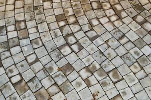 passarela de pedra cinza feita de lajes de pavimentação diagonais quadradas de cimento de concreto com costuras. textura, plano de fundo foto