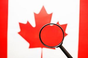 bandeira canadense, olhando através de uma lupa. um estudo da história e cultura do povo do Canadá. o conceito de estudar geografia, costumes foto