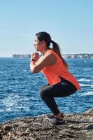 mulher fitness em esportes conjunto treinamento com elástico, pesos, exercícios de ginástica, em frente à água. foto