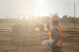 trabalhador segurando rádio operar e controlar o empregado trabalhador para a construção de estradas. construção de estradas jovem trabalhando no canteiro de obras falando com rádio. foto