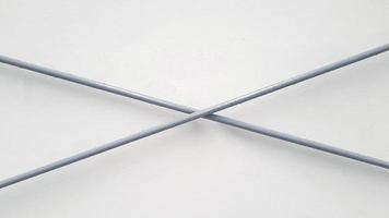 cruz de fio de aço inoxidável cinza ou cinza no fundo da parede branca. linha de ferro e conceito geométrico de forma