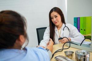 médica asiática usa pressão arterial de mercúrio para determinar a pressão arterial do paciente. foto