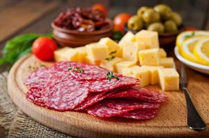 prato de antepasto com salame e queijo em um fundo de madeira foto