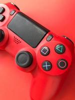 lindo novo joystick de jogo moderno digital vermelho para videogame de computador gamepad em um fundo vermelho foto