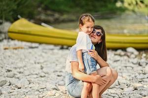 mãe com filha contra canoa na costa rochosa de um rio calmo no parque nacional de triglav, eslovênia. foto