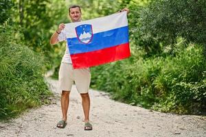 homem segura bandeira eslovena no parque nacional de triglav, eslovênia. foto