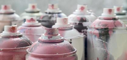 um monte de latas de aerossol sujas e usadas de tinta rosa brilhante. fotografia macro com profundidade de campo rasa. foco seletivo no bico de pulverização foto