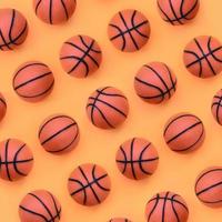 muitas pequenas bolas laranja para jogo de esporte de basquete estão no fundo de textura de papel de cor laranja pastel de moda em conceito mínimo foto