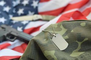 token de etiqueta de cão do exército com balas de 9 mm e pistola deitada na bandeira dos estados unidos dobrada e uniforme de camuflagem foto