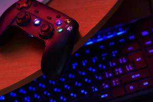 o gamepad moderno encontra-se com o teclado do pc na mesa na cena da sala de jogos escura. conceito de speedrun de videogame ou desafio de competição de esports foto