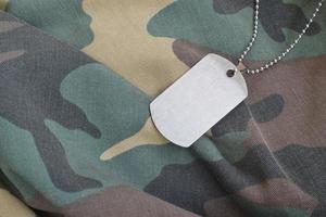 contas militares prateadas com placa de identificação no uniforme de fadiga de camuflagem foto