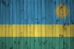 bandeira de ruanda retratada em cores de tinta brilhante na parede de madeira velha. banner texturizado em fundo áspero foto