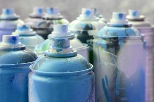 muitas latas de aerossol sujas e usadas de tinta azul brilhante. fotografia macro com profundidade de campo rasa. foco seletivo no bico de pulverização foto