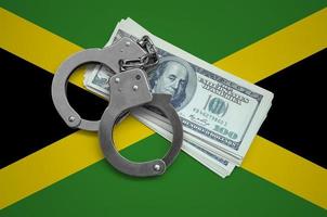 bandeira da jamaica com algemas e um maço de dólares. corrupção monetária no país. crimes financeiros foto