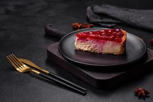 cheesecake saboroso caseiro com geléia e framboesa em um prato preto foto