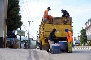 sangatta, leste de kalimantan, indonésia, 2020 - trabalhadores jogam uma lata de lixo em um caminhão de lixo na beira da estrada. foto