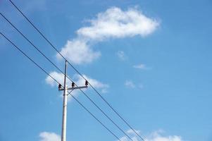 linhas elétricas de pólo elétrico saída de fios elétricos contra o céu azul da nuvem. foto