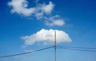 linhas elétricas de pólo elétrico saída de fios elétricos contra o céu azul da nuvem. foto