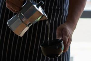 um homem derramando café quente em uma xícara foto