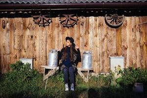 mulher senta-se em um banco com latas de leite em uma fazenda foto