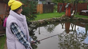 jovem mulher bonita está pescando em um pequeno lago foto