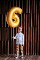 aniversariante em um estúdio fotográfico com uma bola número 6. menino na festa de aniversário. decoração com balões. menino esperto em uma festa foto