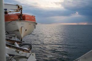 bote salva-vidas paira a bordo do navio, tendo como pano de fundo o mar e o céu. bela paisagem marítima. foto