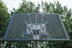 cesta de basquete com uma corrente no contexto das árvores e do céu. campo de esportes ao ar livre. conceito de estilo de vida ativo. vista de baixo. foto