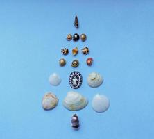 fundo de natal com uma árvore de natal feita de conchas sobre fundo azul. natal tropical e conceito de ano novo foto