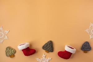 meia de crochê artesanal, presente e árvore de natal em fundo laranja pastel. feliz natal e feliz ano novo conceito. foto