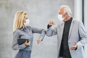 duas pessoas de negócios cumprimentando com cotovelos batendo durante a pandemia de coronavírus no escritório foto