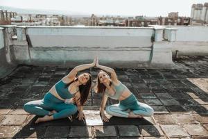 duas mulheres fazendo ioga ao ar livre em um terraço foto