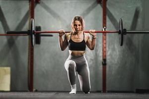 mulher fazendo exercícios de lunges na academia foto