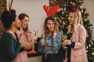 quatro amigas multiétnicas se divertindo e fazendo torradas enquanto comemoram em casa a festa de natal foto