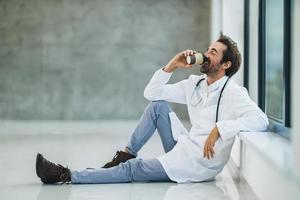 um médico de sucesso tendo coffee-break em um corredor de hospital vazio foto