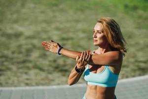 atleta feminina esticando o braço enquanto treinava ao ar livre foto