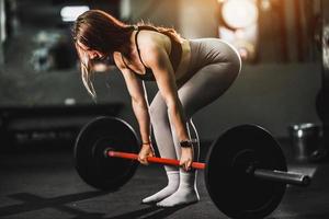 mulher fazendo treinamento com barra na academia foto