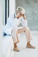 uma médica cansada parecendo preocupada durante uma pausa rápida em um corredor de hospital vazio foto