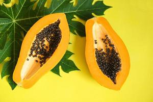 frutas de mamão em backgroud amarelo, fatia de mamão madura fresca fruta tropical com semente de mamão e folhas de mamão foto