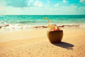 verão de suco de coco fresco com flor na praia mar em clima quente oceano paisagem natureza férias ao ar livre, coco jovem coco frutas tropicais na água de fundo de praia de areia foto