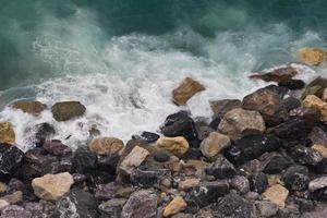 ondas quebrando em uma praia rochosa colorida em vernazza, cinque terre foto