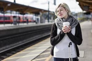 mulher tomando café enquanto espera o trem
