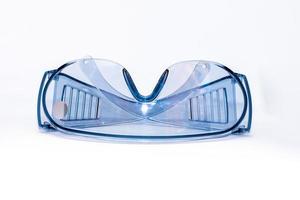 óculos de segurança de plástico azul sobre um fundo branco isolado, close-up. conceito de saúde e segurança ocupacional foto